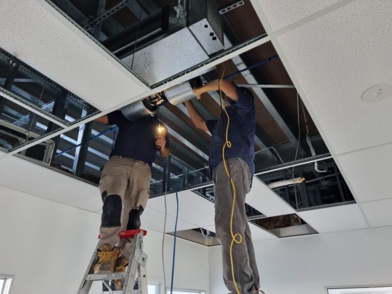 Technicians repairing a commercial system in the ceiling